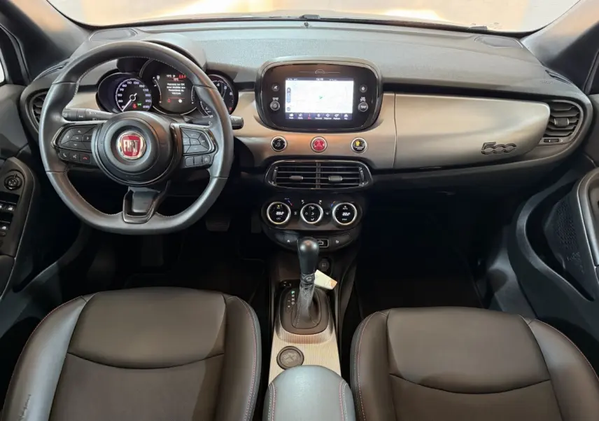 Vue intérieure avant de la Fiat 500X noire, tableau de bord avec écran tactile central et volant multifonctions en cuir.