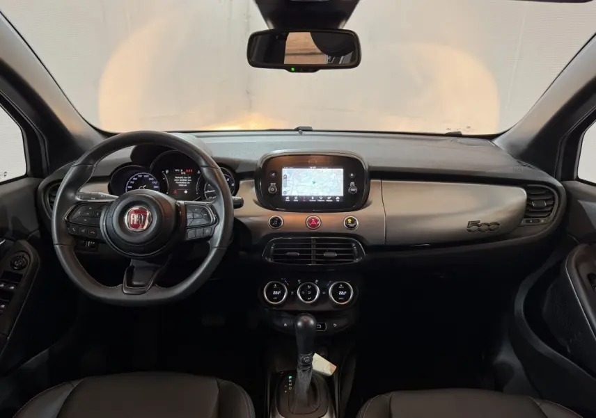 Vue intérieure frontale du tableau de bord noir et gris de la FIAT 500X 2021 avec écran tactile et volant multifonctions.