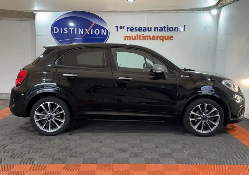 Profil droit d'un FIAT 500X noir 2021 avec badge Sport et jantes alliage distinctives en showroom.