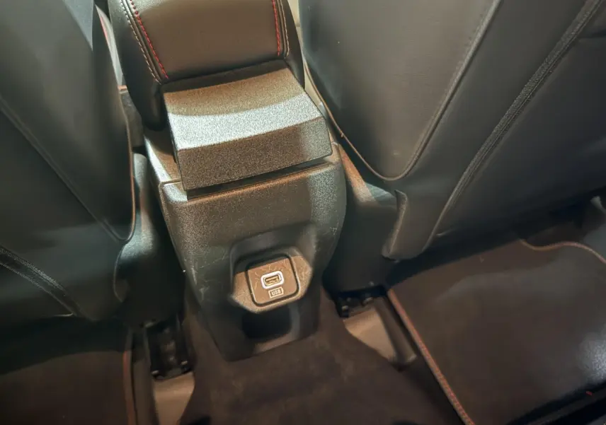 Prise USB arrière entre les sièges noirs avec surpiqûres rouges dans le Fiat 500X noir 2021.