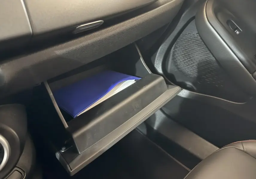 Gant de boîte à gants ouvert côté passager avec manuel bleu dans l'habitacle noir du Fiat 500X 2021.