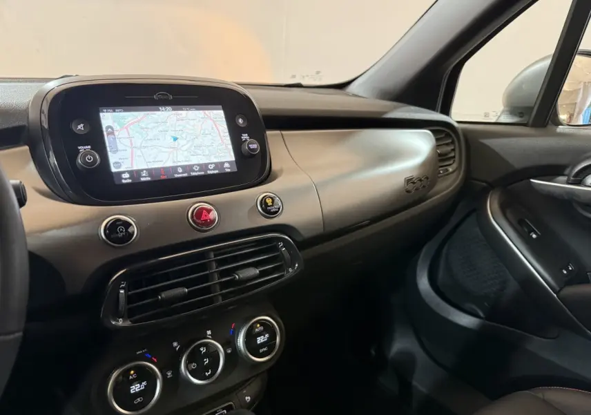 Vue intérieure côté passager du tableau de bord beige et noir avec écran tactile et logo 500 de la Fiat 500X 2021.