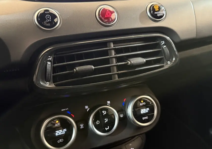 Gros plan sur la console centrale noire du Fiat 500X 2021, montrant les commandes de climatisation et les aérateurs.