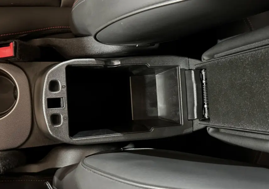 Vue plongeante sur le rangement central noir ouvert entre les sièges avant d'un Fiat 500X 2021.