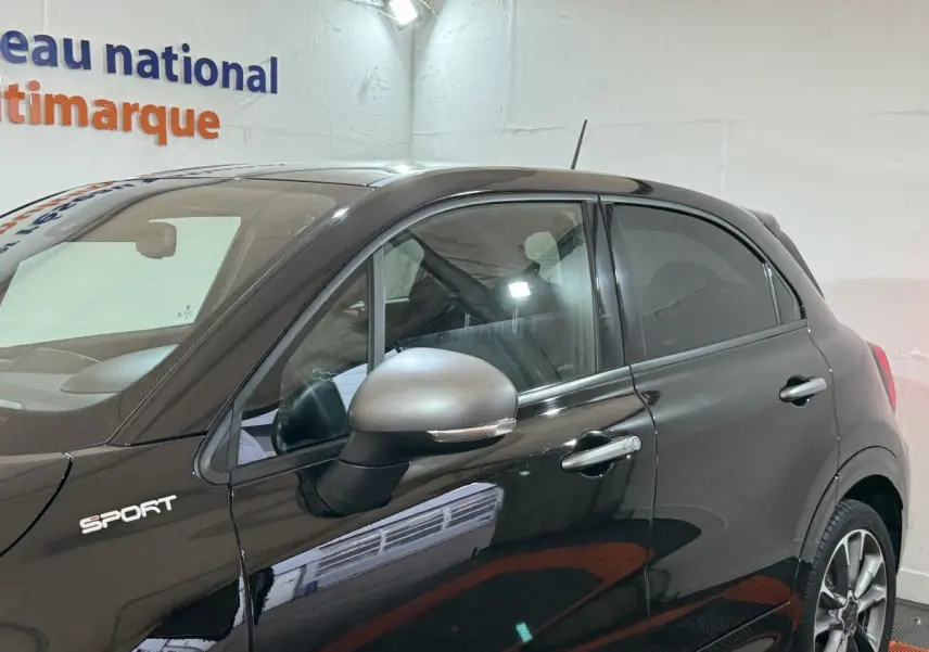 Profil côté gauche d'une FIAT 500X noire version Sport 2021 avec rétroviseur gris et jantes alliage visibles.