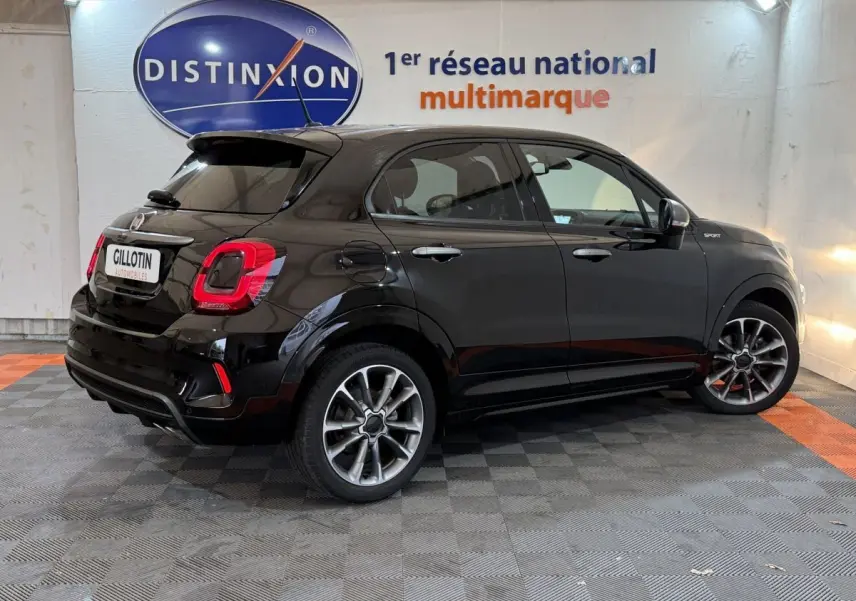 Vue 3/4 arrière droite d'une FIAT 500X noire version Sport, avec jantes alliage et logo distinctif sur l'aile avant.