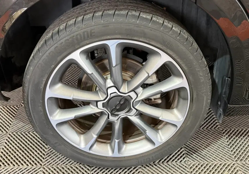 Gros plan sur la roue avant droite noire de la FIAT 500X 2021 avec jante alliage argentée au design moderne.