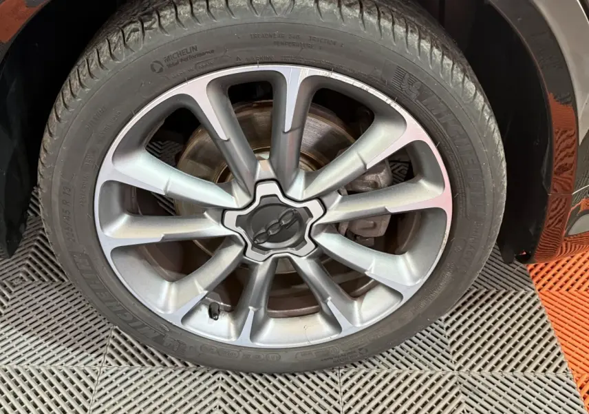 Gros plan sur la jante alliage argentée et le pneu Michelin du côté avant droit d'une FIAT 500X noire Sport 2021.