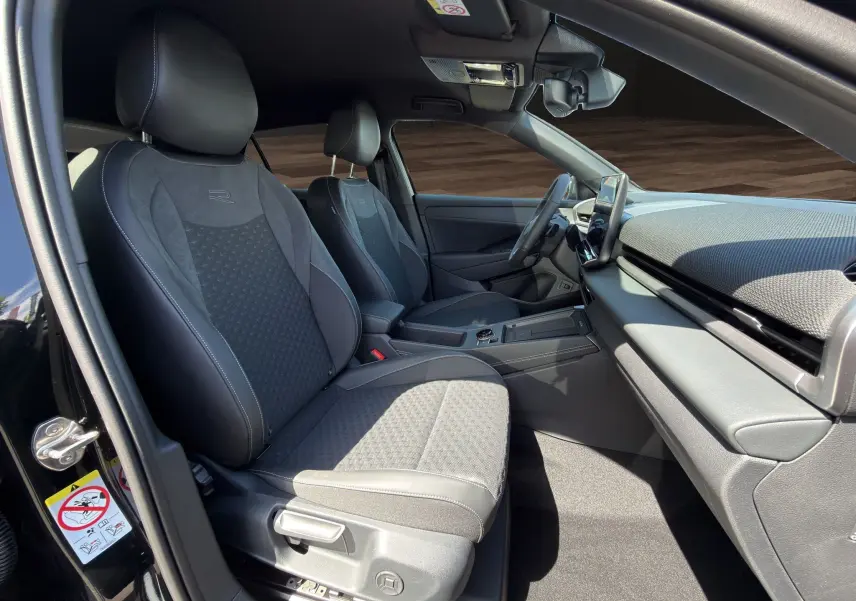 Vue intérieure côté conducteur du Volkswagen T-Roc 2026 noir ébène, sièges en tissu et cuir avec logo R brodé.