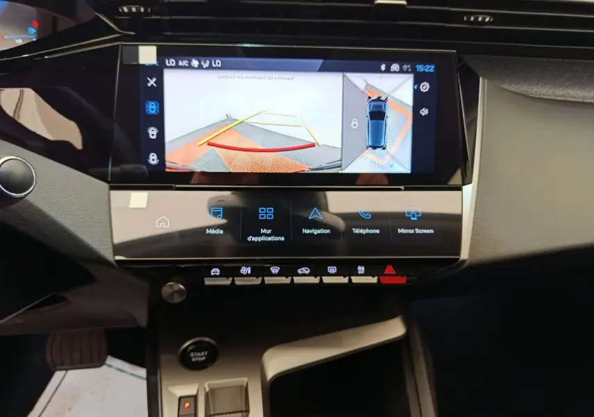 Vue intérieure centrée sur l’écran tactile et la console centrale de la Peugeot 308 blanche avec affichage caméra de recul.