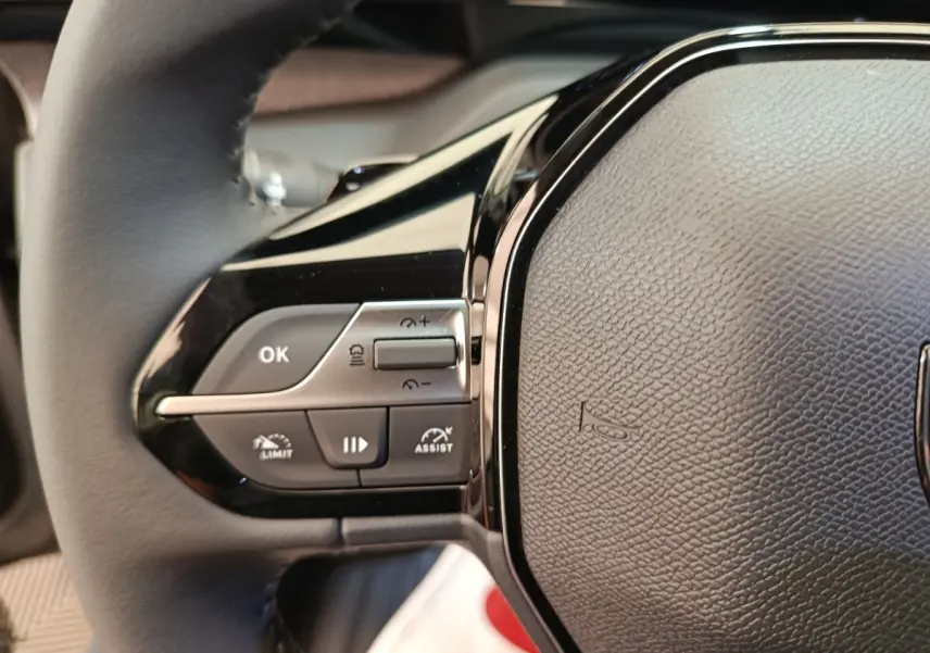 Gros plan sur le côté gauche du volant cuir multifonctions de la Peugeot 308 BlueHDi 130 CH EAT8 Allure 2026.