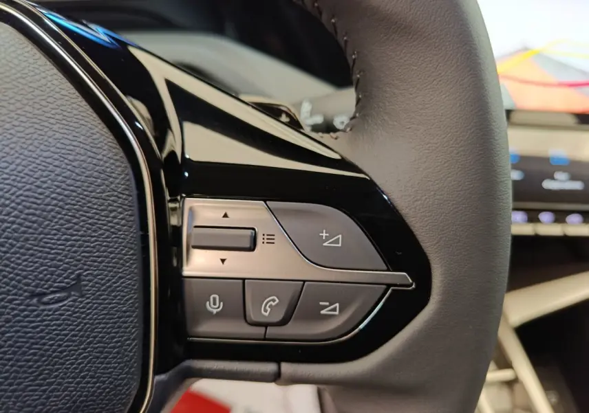 Gros plan sur le côté droit du volant cuir multifonctions de la Peugeot 308 blanche, avec commandes audio et appel.