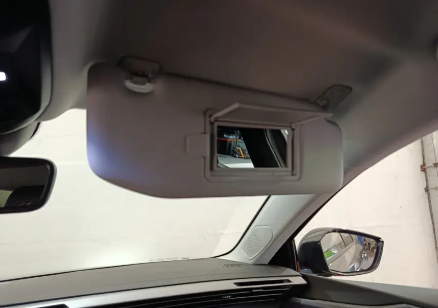 Vue intérieure côté conducteur du pare-soleil avec miroir ouvert et rétroviseur latéral droit visible d’une Peugeot 308 blanche.
