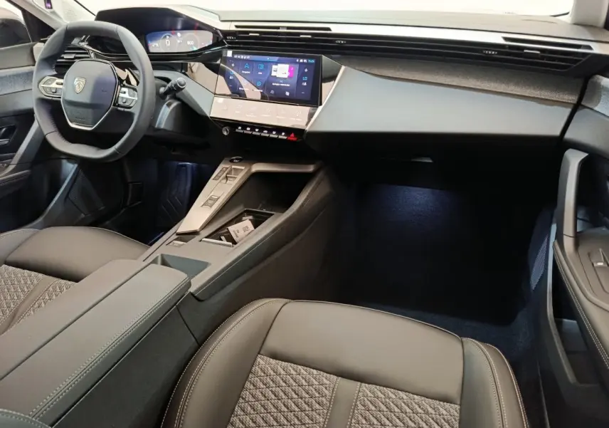 Vue intérieure côté conducteur de la Peugeot 308 2026, volant cuir multifonctions et écran tactile central lumineux.