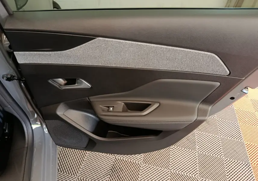 Vue intérieure de la porte avant gauche de la Peugeot 308 blanche, avec garniture tissu et cuir gris.