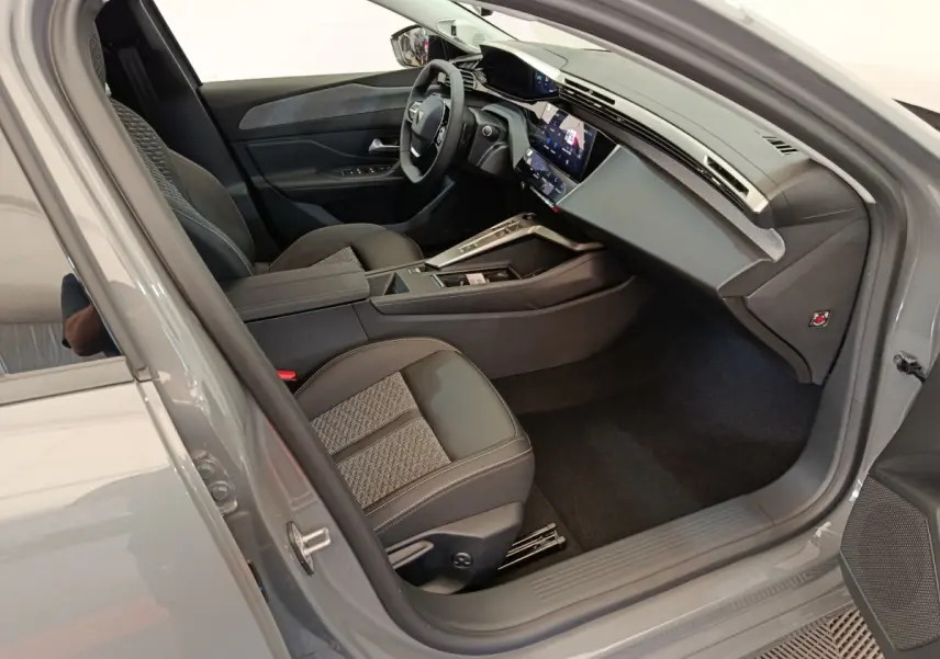 Intérieur côté conducteur de la Peugeot 308 2026, sièges cuir et tissu, tableau de bord moderne avec écran tactile.