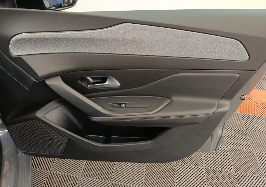 Vue intérieure de la porte côté droit de la Peugeot 308 blanche, avec garniture tissu gris et commandes de fenêtre.