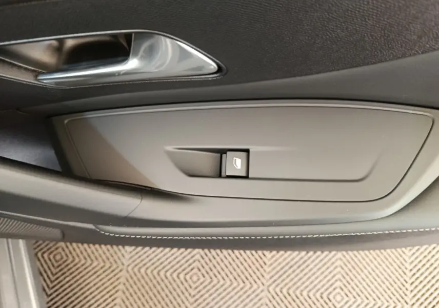 Gros plan sur la commande de lève-vitre côté conducteur de la Peugeot 308 blanche, finition Allure 2026.