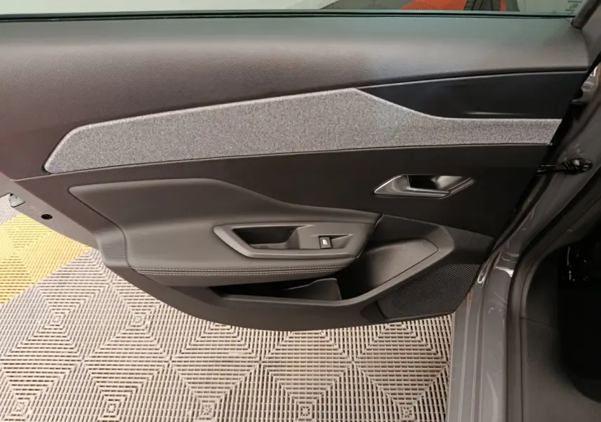 Vue intérieure de la porte avant gauche de la Peugeot 308 2026, avec garniture noire et tissu gris.