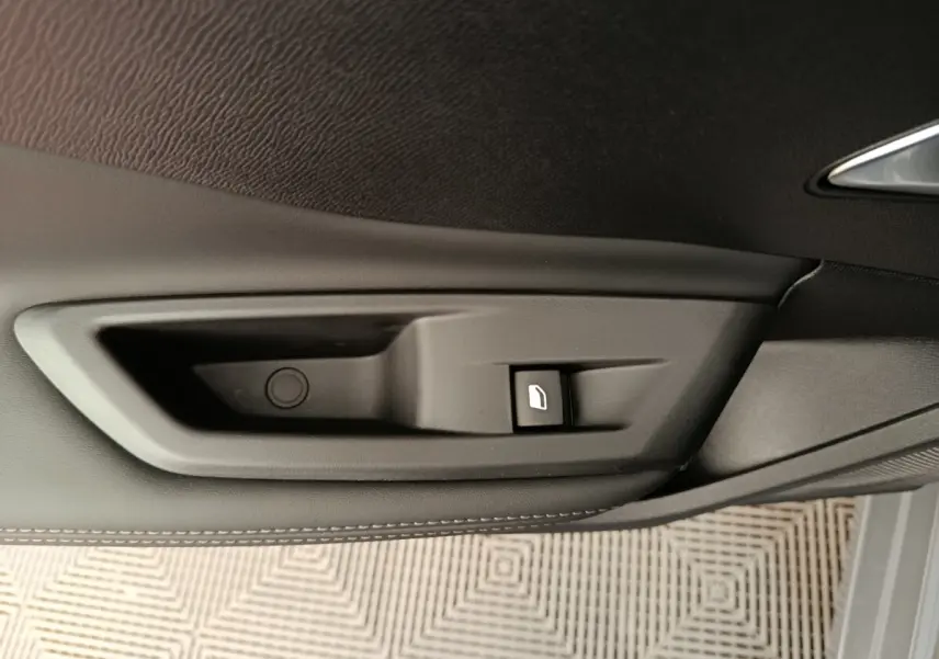 Détail de la commande de lève-vitre côté porte intérieure noire d'une Peugeot 308 blanche 2026.