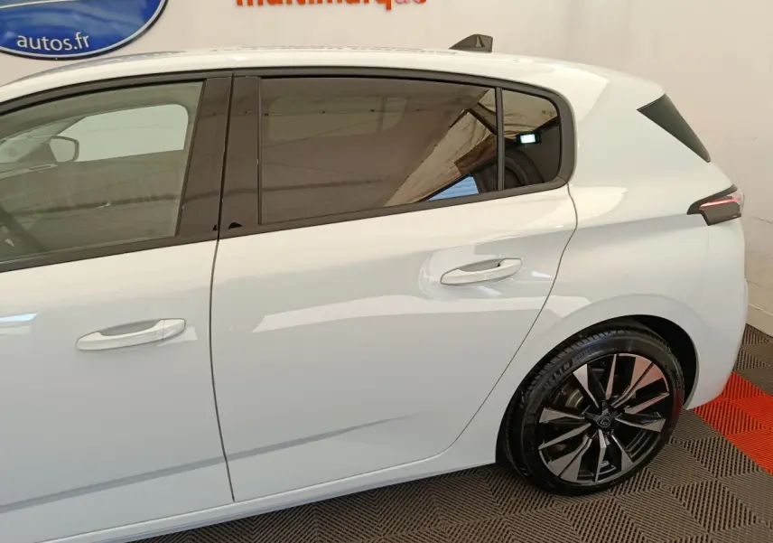Vue latérale droite d'une Peugeot 308 blanche avec jantes alliage noires et vitres teintées.