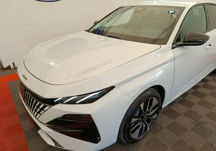 Peugeot 308 blanc vue 3/4 avant droit, avec calandre distinctive et jantes alliage noires brillantes.