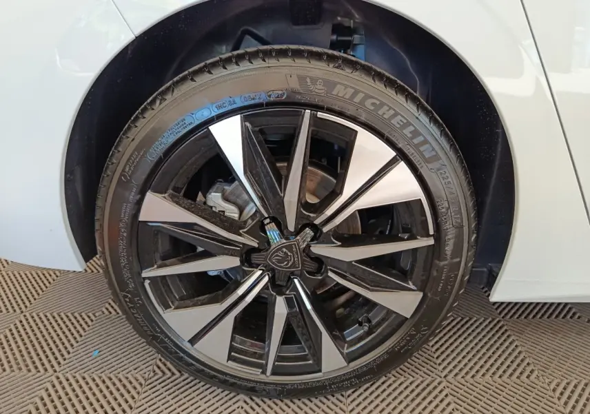 Gros plan sur la roue avant droite blanche d'une Peugeot 308 2026 avec jante alliage noire et argentée.