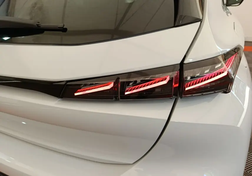 Gros plan sur le feu arrière droit rouge d’une Peugeot 308 blanche, vue arrière en intérieur.