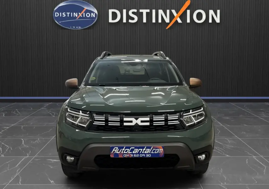 Vue frontale d'un Dacia Duster 2024 kaki lichen avec calandre noire et phares LED, en showroom Distinxion.