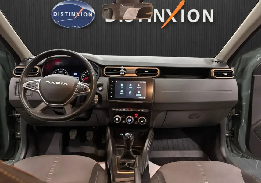 Vue intérieure avant du Dacia Duster 2024 kaki lichen, tableau de bord avec écran tactile et volant multifonction.
