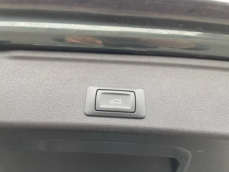 Bouton d'ouverture électrique du coffre sur la partie intérieure d'un Audi A4 Avant vert vue rapprochée.