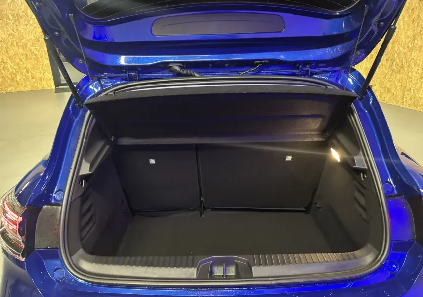 Coffre ouvert vu de l'arrière d'une Renault Clio 2024 bleu iron, montrant l'espace de chargement intérieur noir.