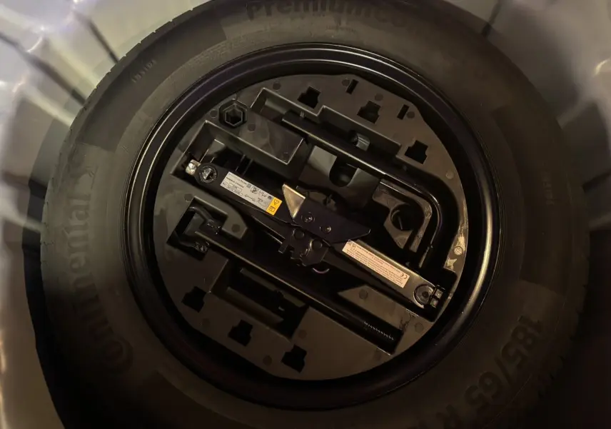 Gros plan sur la roue de secours noire et ses outils de bord dans le coffre d'une Renault Clio Bleu Iron 2024.