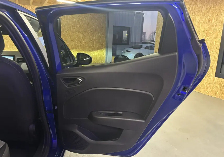 Vue intérieure de la porte arrière droite bleu iron d’une Renault Clio 2024, montrant la garniture noire et la poignée intégrée.