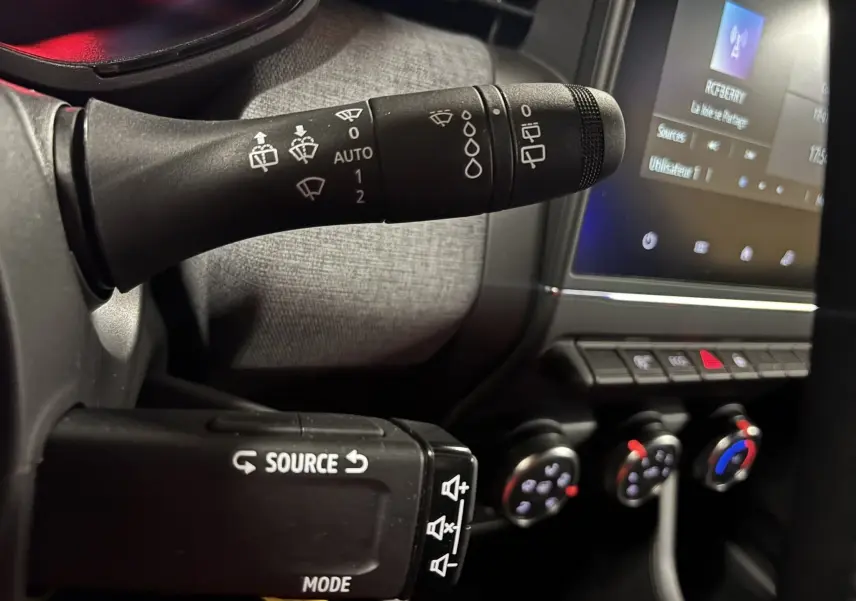 Gros plan sur les commandes au volant de la Renault Clio 2024, avec levier d’essuie-glace et commandes audio visibles.