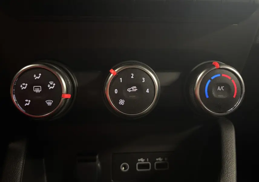 Gros plan sur les commandes de climatisation de la Renault Clio 2024 bleu Iron, avec réglages ventilation, air et température.
