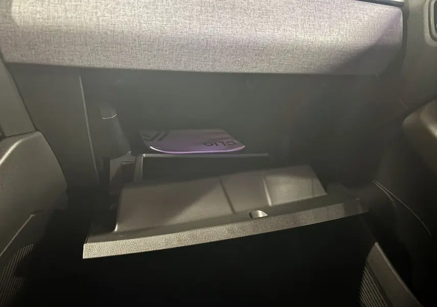 Gros plan sur la boîte à gants ouverte du Renault Clio 2024, intérieur gris et manuel visible à l'intérieur.