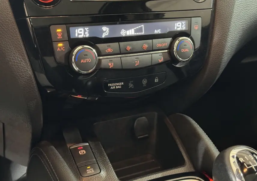 Gros plan sur la console centrale du Nissan Qashqai gris foncé, montrant la climatisation digitale et le frein à main électrique.