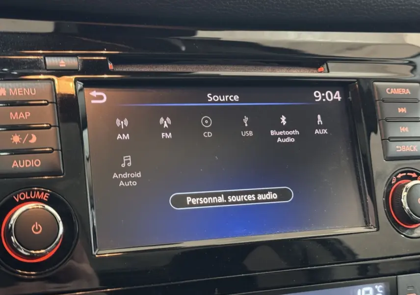Écran tactile central du Nissan Qashqai 2019 affichant les sources audio, entouré de boutons de commande noirs.