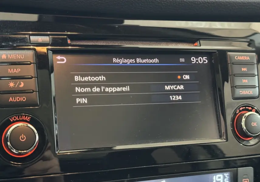 Écran tactile central du Nissan Qashqai 2019 affichant les réglages Bluetooth, entouré de boutons noirs avec marquages orange.