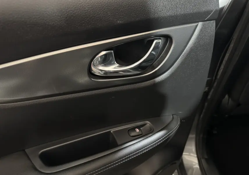 Poignée intérieure de porte arrière droite du Nissan Qashqai gris foncé, avec bouton de verrouillage et garniture noire.