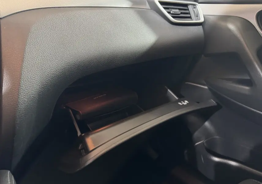 Vue intérieure du côté passager du Nissan Qashqai 2019, boîte à gants ouverte avec manuel visible, tableau de bord noir.