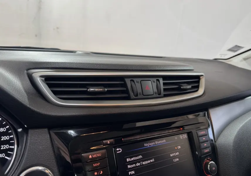 Gros plan sur la console centrale du Nissan Qashqai gris foncé, mettant en valeur l'écran tactile et les commandes.