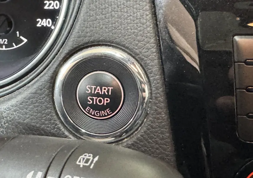 Gros plan sur le bouton Start Stop Engine entouré de chrome dans l’habitacle noir du Nissan Qashqai gris foncé.