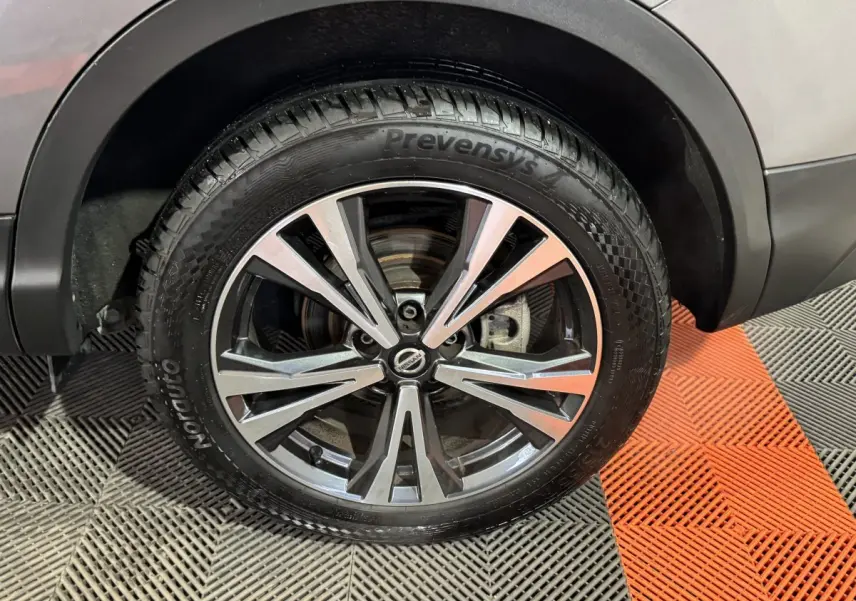 Gros plan sur la roue avant droite du Nissan Qashqai gris foncé, avec jante alliage bicolore et pneu Prevensys.