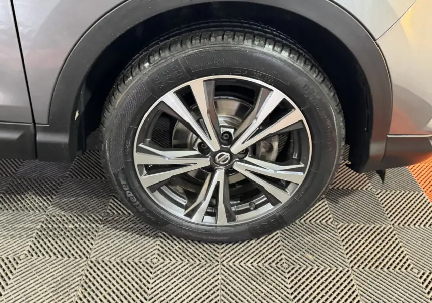 Gros plan sur la roue avant droite du Nissan Qashqai gris foncé avec jante alliage à rayons doubles.