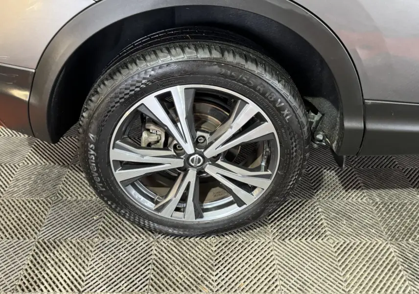 Gros plan sur la roue avant droite du Nissan Qashqai gris foncé, mettant en valeur la jante alu et cuir.