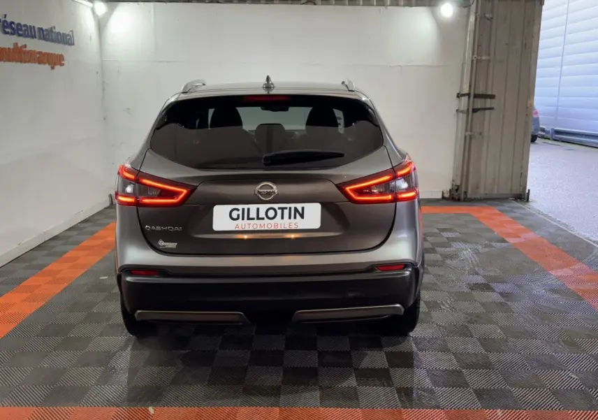 Vue arrière du Nissan Qashqai gris foncé 2019 avec feux LED allumés dans un garage aux bandes orange au sol.