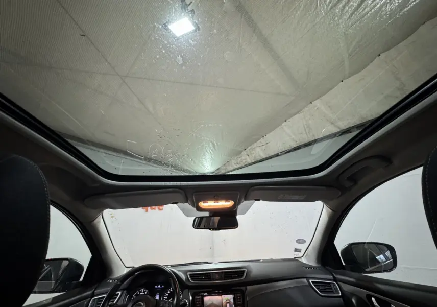 Vue intérieure avant du Nissan Qashqai 1.3 DIG-T 140 N-Connecta avec toit panoramique et tableau de bord noir.