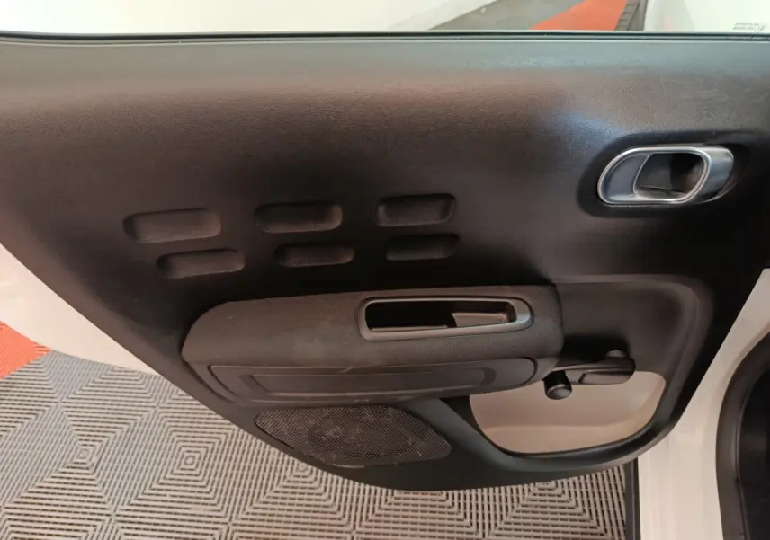 Vue intérieure sur la porte avant droite noire et blanche de la Citroën C3 avec poignée et manivelle de vitre.